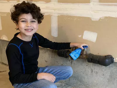 A Boy Next To A House Water Shutoff